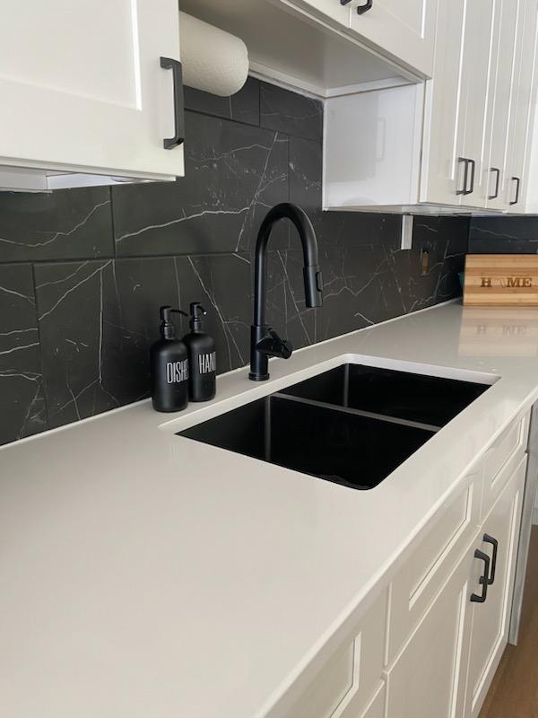 Dark veined backsplash above a light countertop and black sink