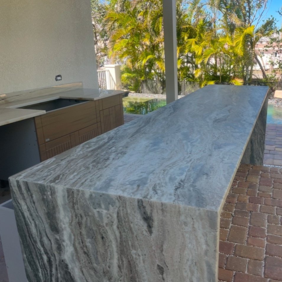 Patterned stone waterfall bar beside an outdoor cooking area